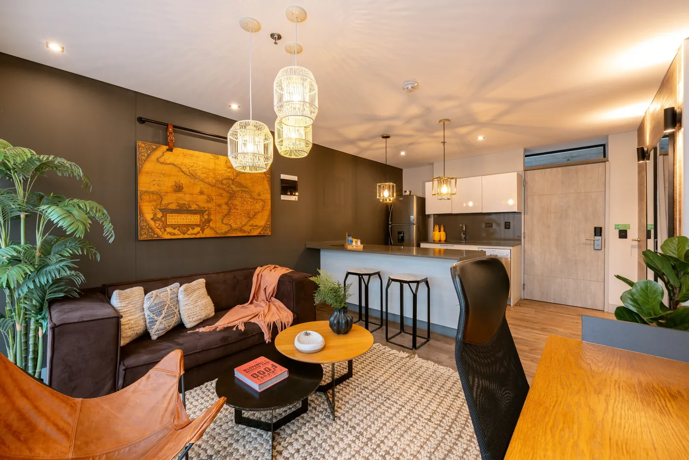 Living room with leather sofa and kitchen in a one-bedroom furnished apartment at Loma Verde, Medellín