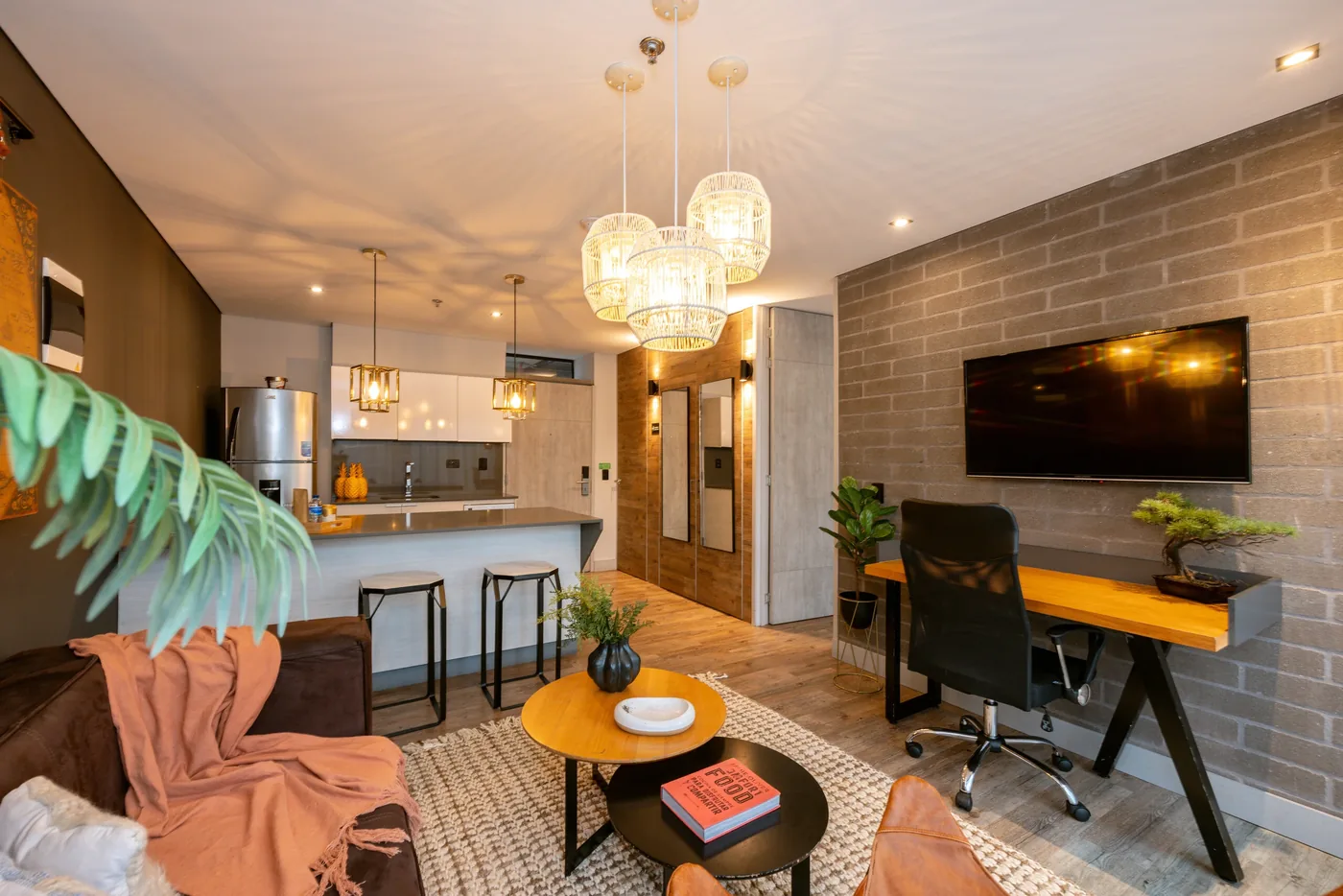 Living room with TV wall and desk in a one-bedroom furnished apartment at Loma Verde, Medellín