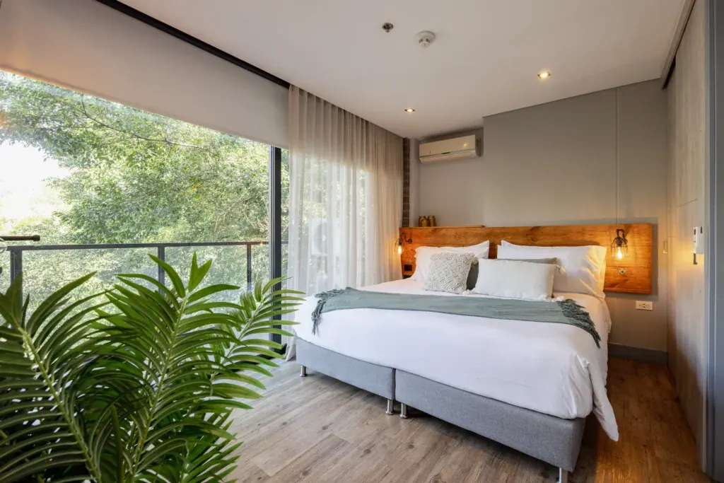 King-size bedroom with a balcony overlooking the greenery of El Poblado in a furnished apartment at Loma Verde, Medellín
