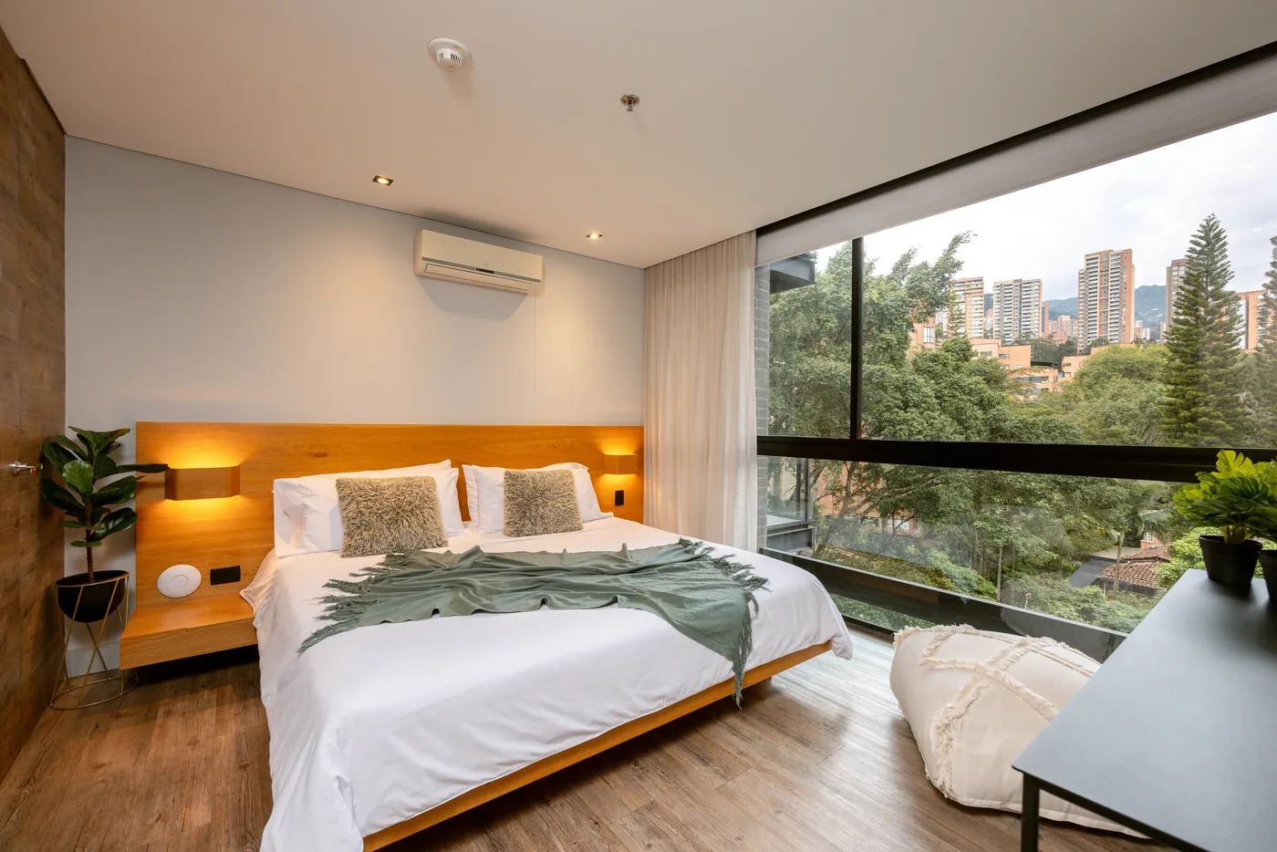 Bedroom with balcony and city views in a one-bedroom furnished apartment at Loma Verde, Medellín