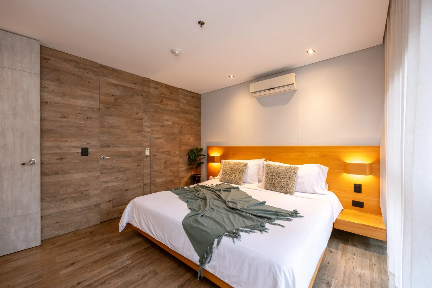 Bedroom with wood-paneled wall in a one-bedroom furnished apartment at Loma Verde, Medellín
