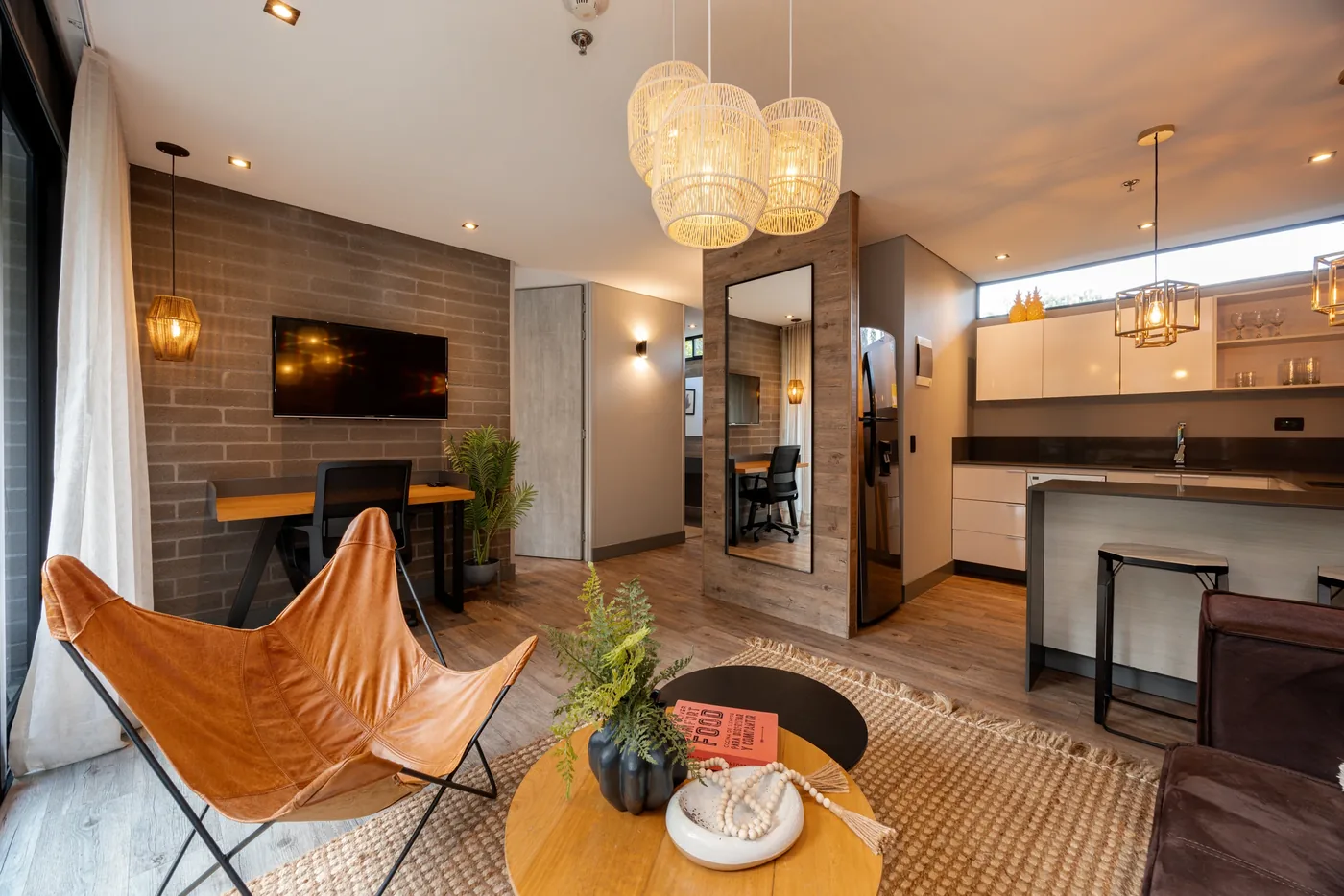 Living area with leather chair looking to the kitchen in a one-bedroom furnished apartment at Loma Verde, Medellín