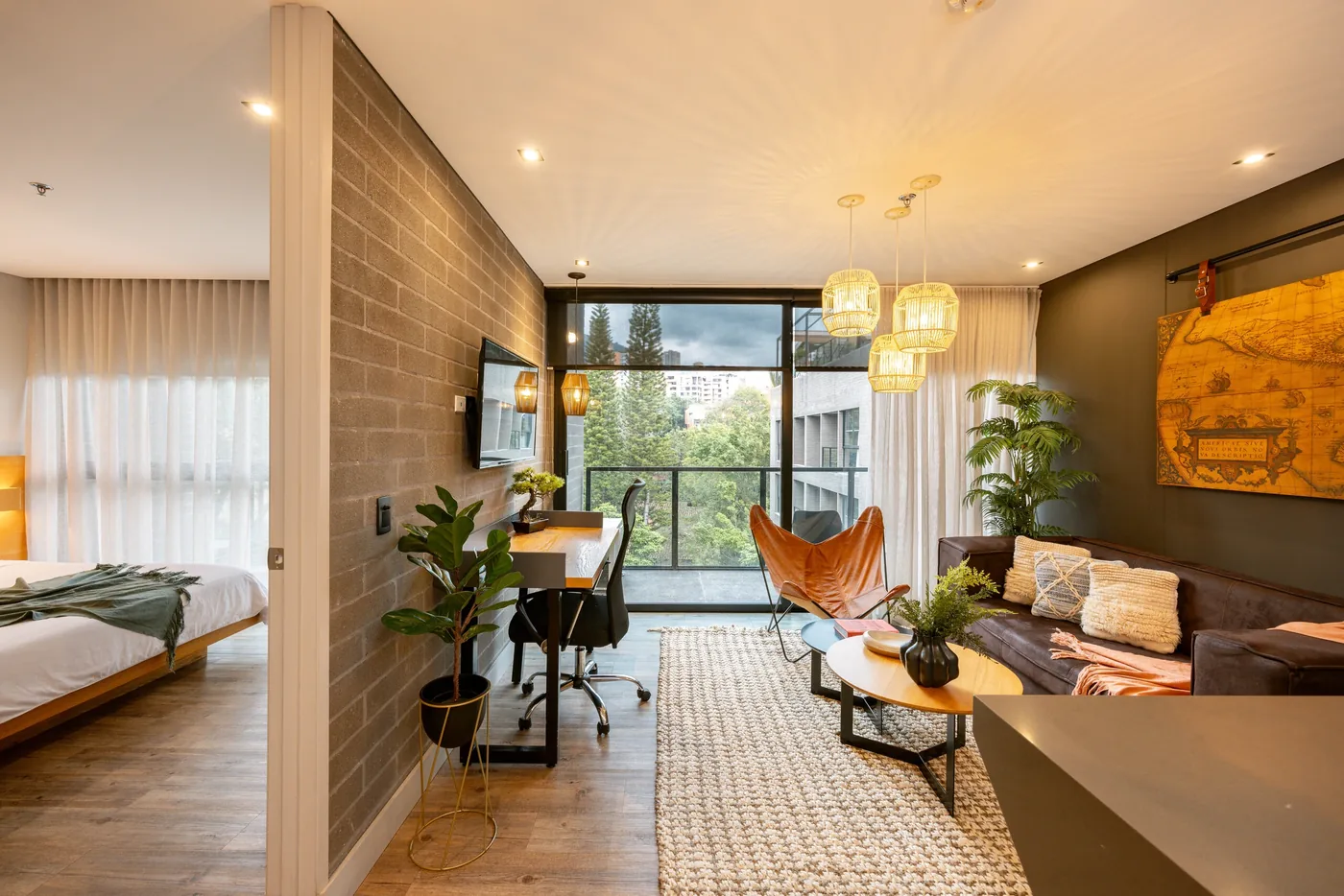 Open-plan living space and bedroom in a one-bedroom furnished apartment at Loma Verde, Medellín